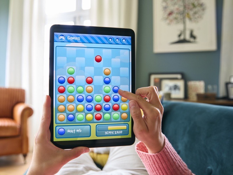 A tablet held in both hands, a puzzle game on the screen.